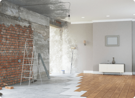 An interior undergoing renovation with exposed brick, tools, and new flooring being installed.